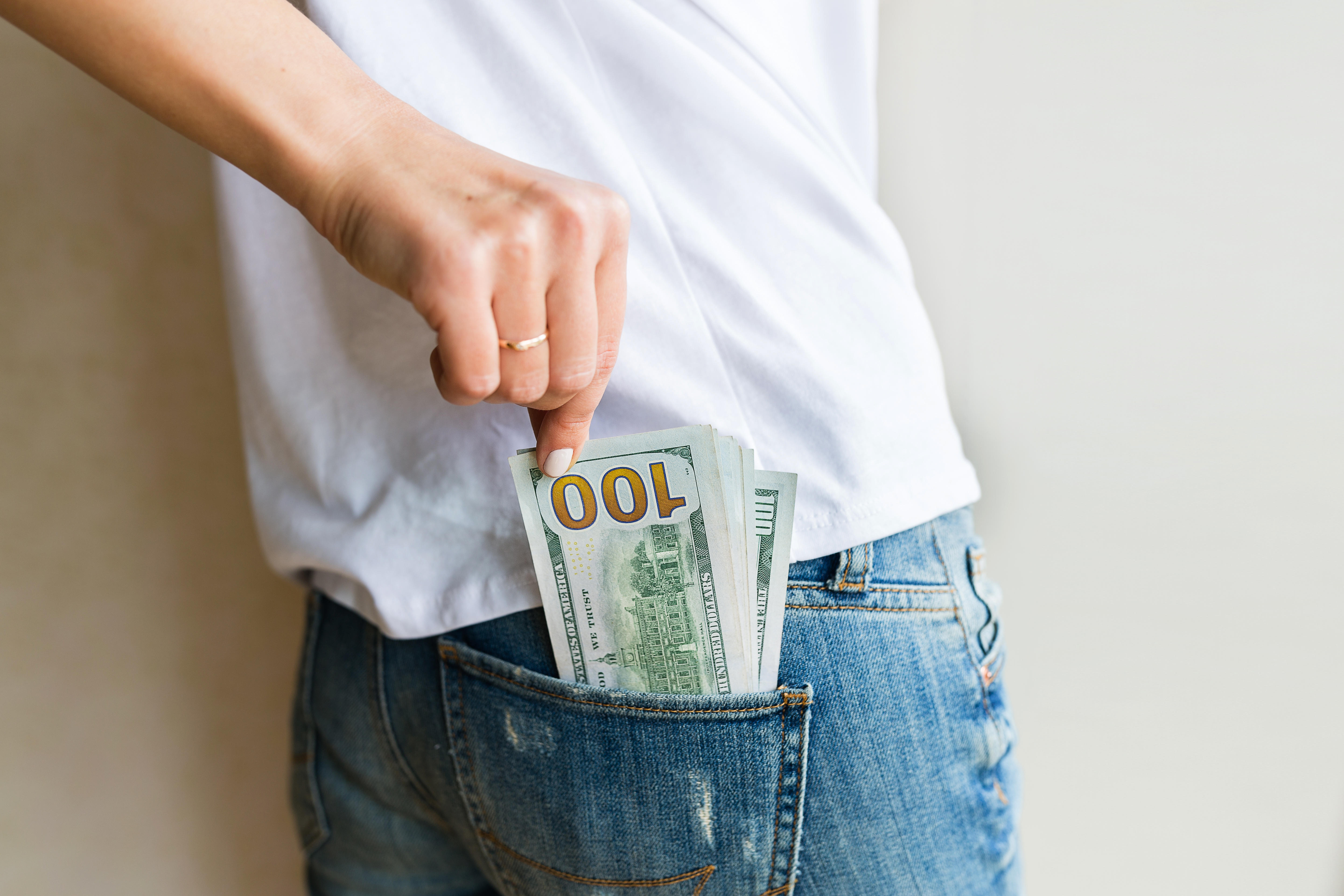 A Woman Pulling Dollar Bills Out Of Her Back Pocket After Securing A Quick Cash Loan